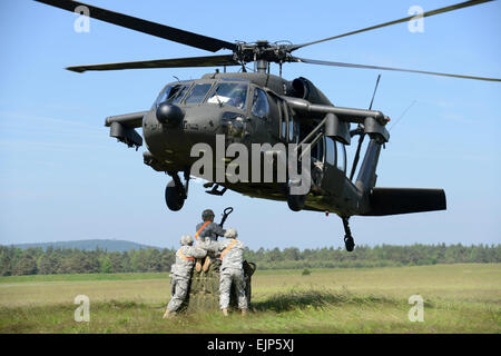 U.S. Army soldiers, assigned to 18th Combat Sustainment Support Battalion, attach the hook during sling load operations at the Grafenwoehr Training Area, Germany, June 13, 2013. Helicopter sling load operations are the key to moving supplies and equipment to remote locations.  Visual Information Specialist Markus Rauchenberger/released Stock Photo