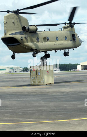 Soldiers from the Company E, 4th Battalion, 101st Aviation Regiment, attach a container to a CH-47F Chinook helicopter slingload hook in order to stand up a jump-forward arming and refueling point during a Joint Operations Aviation Exercise at Fort Bragg, N.C., Aug. 22. The jump-FARP will give pilots the opportunity to stay in the vicinity of their mission. Stock Photo
