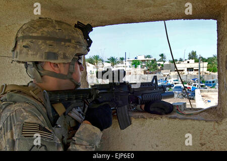 U.S. Army Spc. Anthony Locke provides security from a window at an Iraqi police station in Daliabas, Iraq, April 13, 2009. Locke is assigned to the 25th Infantry Division's 3rd Battalion, 21st Infantry Regiment, 1st Stryker Brigade Combat Team. U.S. Navy Petty Officer 2nd Class Walter J. Pels Stock Photo