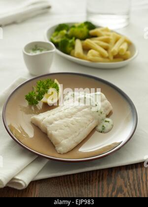 Plated meal of plain fillet of haddock or cod fish with lemon parsley and sauce Stock Photo