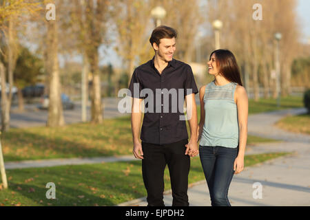 Happy couple laughing while taking a walk in a park Stock Photo