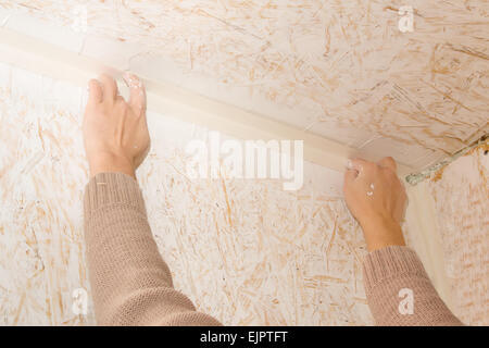 Female hands glued paper tape on the joint OSB Stock Photo