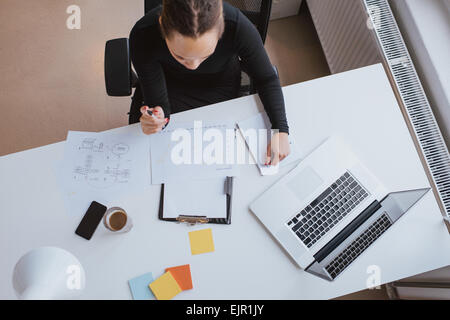 Top view of young woman reviewing chart. businesswoman analyzing financial data. Female working on company data projections. Stock Photo