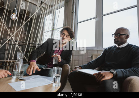 Young executive explaining something to his team in a meeting. Young man discussing business strategy with colleagues during a m Stock Photo