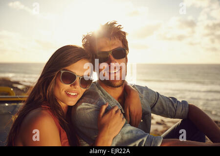 Portrait of beautiful young couple wearing sunglasses looking at camera while on a road trip. Young man and woman. Stock Photo