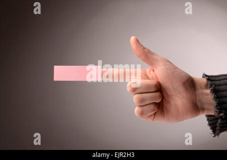 Male hand making a pistol with a sticky note on the index finger Stock Photo