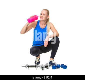 blonde woman wearing fitness clothing and drinking after exercising with weights Stock Photo