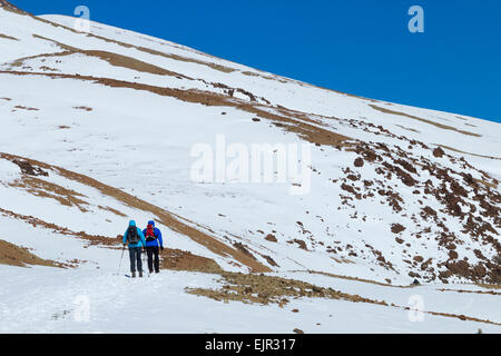 Man and woman walking in snow covered Teide National Park on Tenerife, Canary Islands, Spain Stock Photo