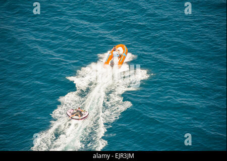 Inflatable toy being towed behind a speed boat during summer tropical sea holiday vacation Stock Photo