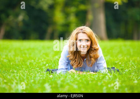 beautiful young woman lying in green grass with happy mood Stock Photo