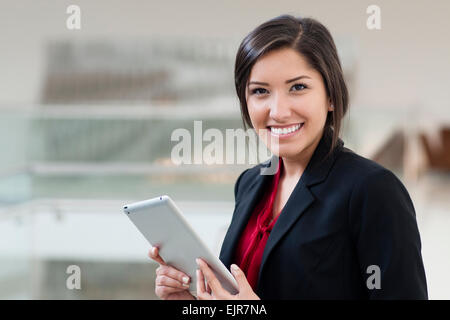 Smiling Hispanic businesswoman holding digital tablet Stock Photo
