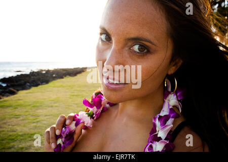 Caucasian woman wearing flower lei near ocean
