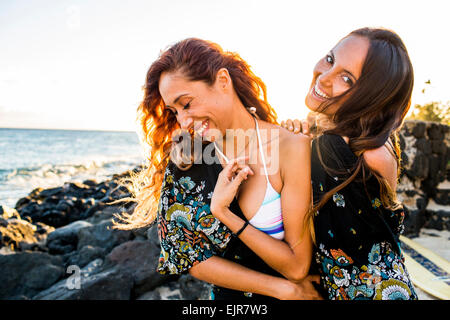 Women laughing on rocky beach Stock Photo