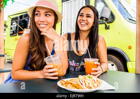 Pacific Islander women eating and drinking near food cart Stock Photo