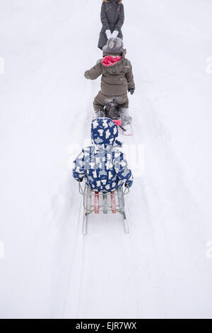 Family playing on sleds on snowy street Stock Photo