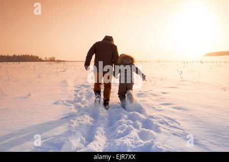 Mari father and son walking in snowy field Stock Photo