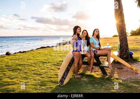 Pacific Islander women smiling on picnic table near beach Stock Photo