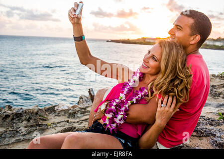 Couple taking cell phone photograph on beach
