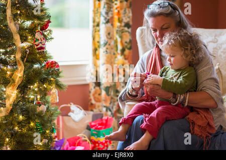 Caucasian grandmother and grandson opening presents near Christmas tree Stock Photo