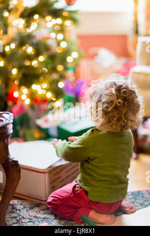 Caucasian baby boy opening presents near Christmas tree
