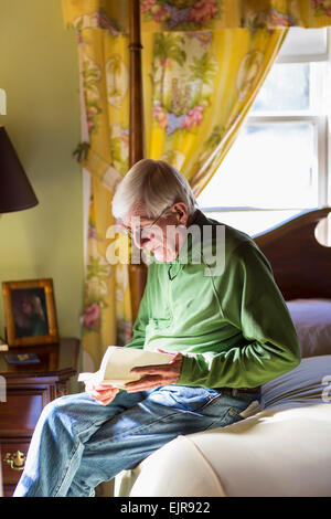 Older Caucasian man reading on bed Stock Photo