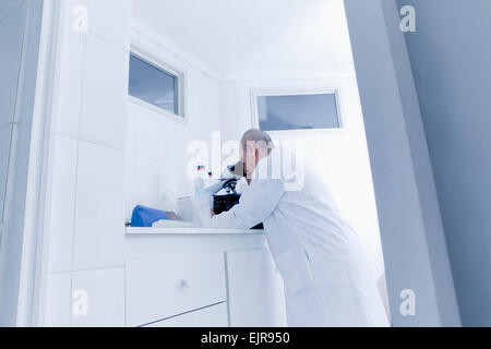 Hispanic scientist using microscope in lab Stock Photo