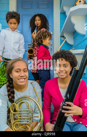 Pacific Islander family holding musical instruments on front stoop Stock Photo