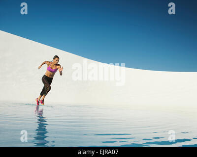 Mixed race woman running on water surface Stock Photo