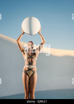 Caucasian woman holding sphere in swimming pool Stock Photo