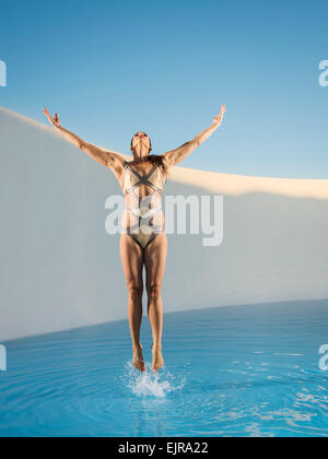 Caucasian woman jumping on swimming pool Stock Photo