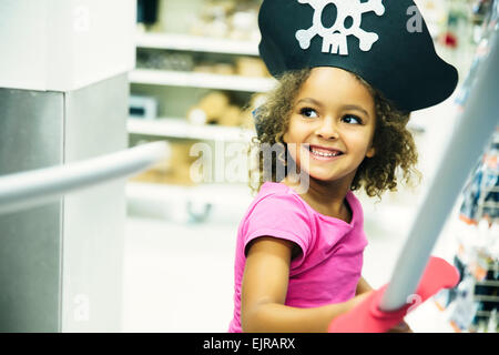 Mixed race girl playing dress-up with pirate hat and sword Stock Photo