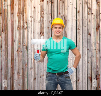 smiling manual worker in helmet with paint roller Stock Photo