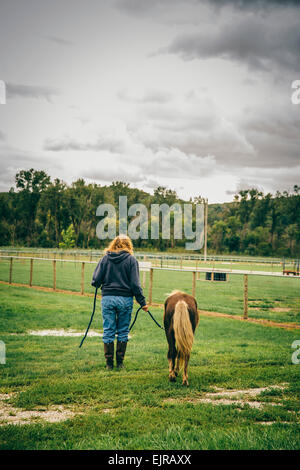Caucasian woman walking miniature horse on ranch Stock Photo