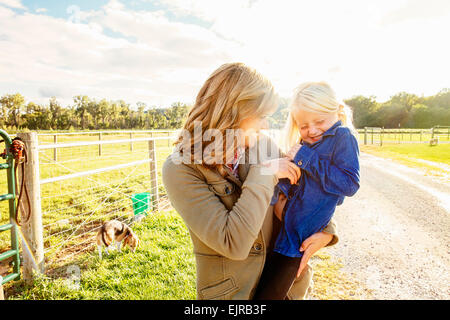 Caucasian mother tickling daughter on rural road Stock Photo