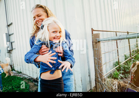 Caucasian mother playing with daughter on farm