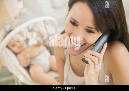 Close up of mixed race mother talking on telephone near baby Stock Photo