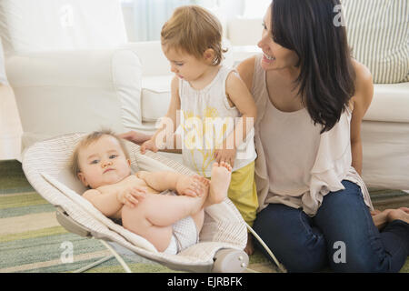 Mother and daughter admiring baby on living room floor