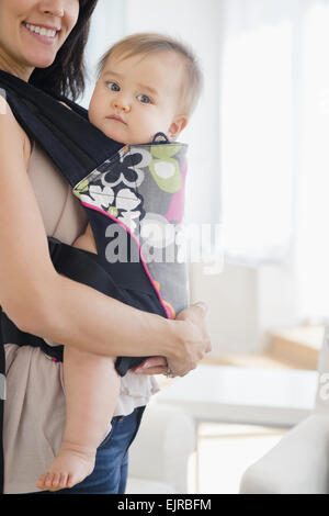 Mixed race mother carrying baby in baby carrier Stock Photo