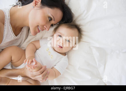 Overhead view of mixed race mother laying with baby on bed Stock Photo