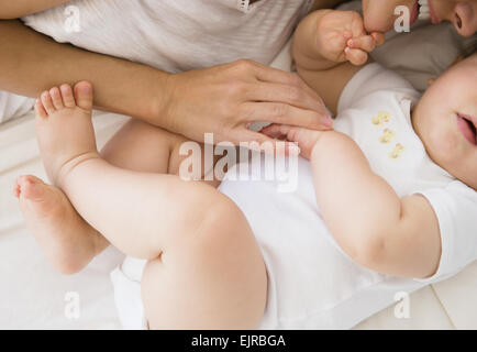 Overhead view of mixed race mother laying with baby on bed Stock Photo
