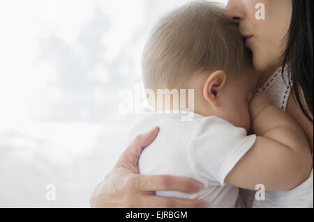 Close up of mixed race mother kissing baby on forehead Stock Photo