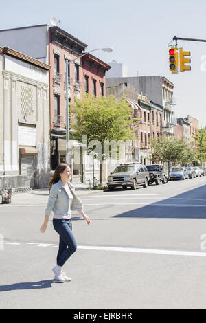 Caucasian woman crossing urban street Stock Photo