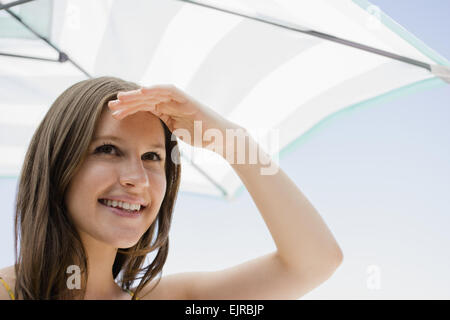 Caucasian woman shielding her eyes from sun Stock Photo