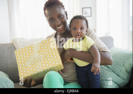 Black mother and son holding gift on sofa Stock Photo