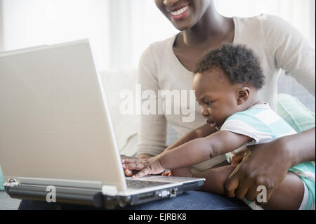 Black mother and son using laptop on sofa Stock Photo
