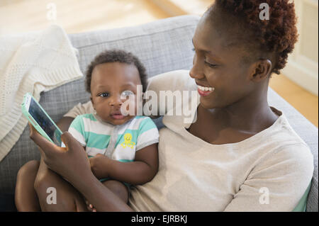 Black mother and son using cell phone on sofa Stock Photo