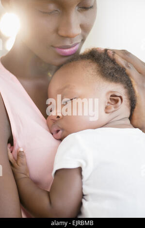 Black mother holding sleeping son Stock Photo