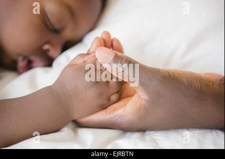 Close up of Black mother holding hand of sleeping baby
