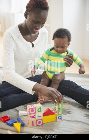 Black mother playing with baby boy in living room
