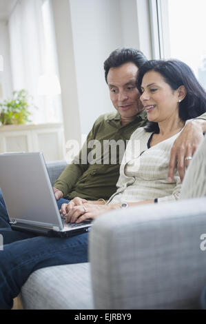 Couple using laptop on sofa in living room Stock Photo
